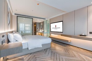 A modern hotel room with a large bed, a television, and a herringbone-patterned floor. - Rezen Hotel Meiyo (Suining)