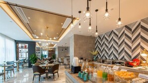 Um lobby de hotel moderno com área de buffet, assentos e bar.