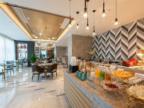 Un vestíbul d'hotel modern amb zona de buffet, seients i bar.