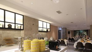 Um saguão de hotel com balcão de recepção, área de estar e grandes janelas.