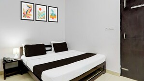 Quarto de hotel com cama, mesa de cabeceira, luminária e três obras de arte emolduradas na parede.