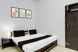 A hotel room with a bed, bedside table, lamp, and three framed artworks on the wall. - Super OYO Hotel O Indira Nagar (Lucknow)
