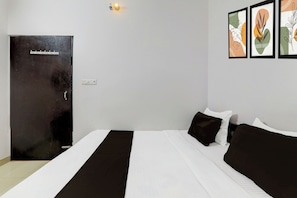 A hotel room with a bed, a door, and wall-mounted artwork. - Super OYO Hotel O Indira Nagar (Lucknow)