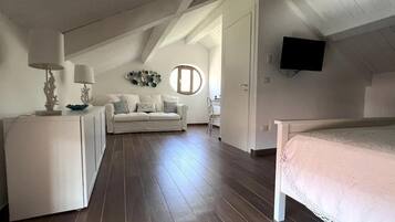 Ein Schlafzimmer mit einem Bett, einem Schreibtisch, einem Sessel, einer Couch und einem Fernseher.