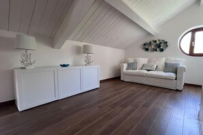 Ein Zimmer mit einer weißen Couch, einer weißen Kommode und einem dekorativen Wandbild.