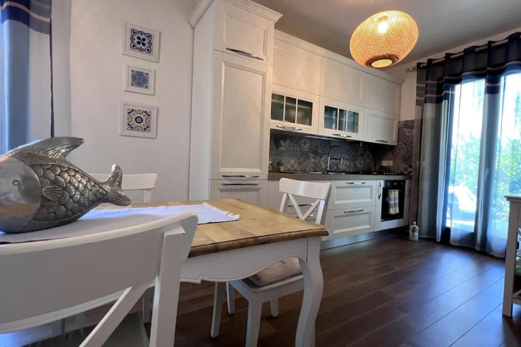 Una cucina moderna con mobili bianchi, un tavolo da pranzo in legno e una decorazione a forma di pesce.