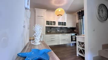Una cucina moderna con mobili bianchi, un piano di lavoro in legno e una stella marina decorativa.