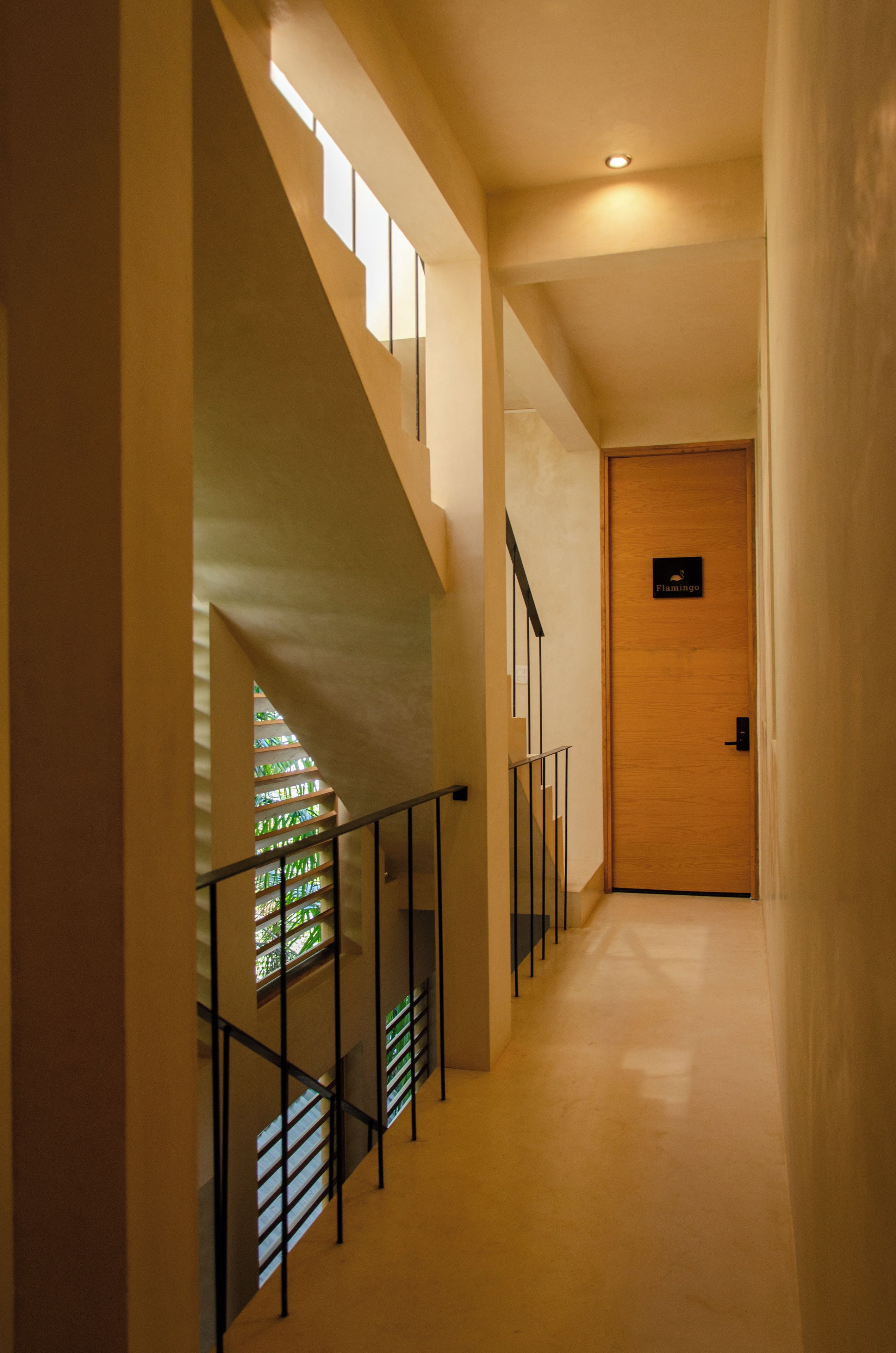 A modern interior with a staircase, a wooden door, and a sign.