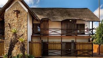 A two-story building with a stone facade, wooden balconies, and a thatched roof.