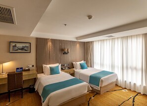 A hotel room with two beds, a desk, a chair, a lamp, a picture on the wall, and a window with curtains. - Four Seasons Apple Hotel (Beijing)