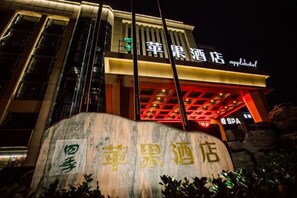 A hotel with a sign that reads 'Apple Hotel' and a large stone with Chinese characters. - Four Seasons Apple Hotel (Beijing)