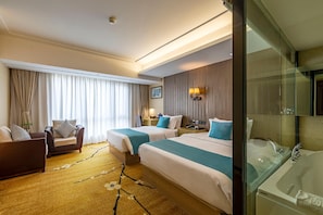 Ein Hotelzimmer mit zwei Betten, einem Sofa, einem Schreibtisch und einem Badezimmer mit Badewanne.