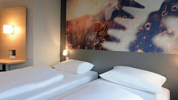 A hotel room with two beds, a wall-mounted light, and a large abstract painting.