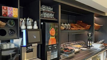 A self-service breakfast station with a coffee machine, various food containers, and a display of breakfast items.