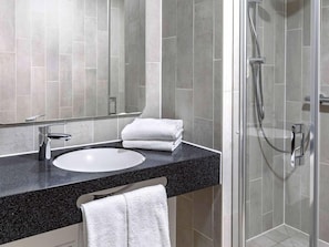 A modern bathroom with a sink, mirror, and shower. - Ibis Budget Duesseldorf Willich (Willich)