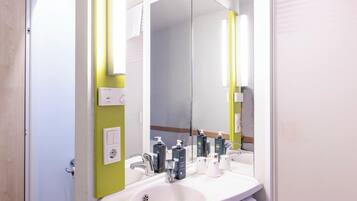 A bathroom with a white sink, mirror, and green wall.