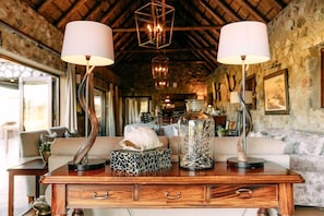 A wooden table with two lamps, a decorative box, and a glass jar with branches.
