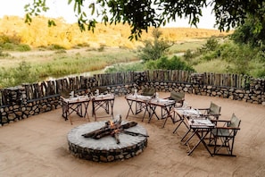 An outdoor seating area with tables and chairs arranged around a central fire pit. - Last Word Kitara Camp (Mpumalanga)