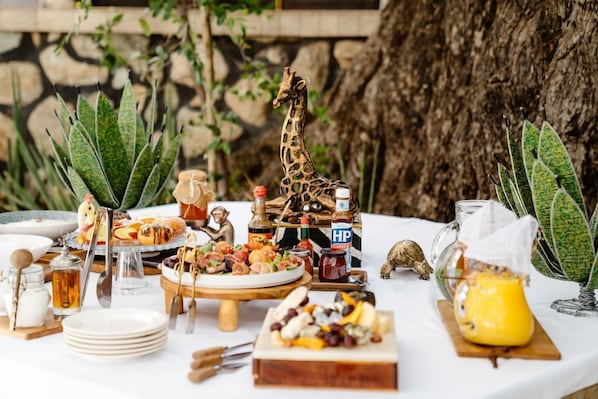 A table set with various food items, a giraffe figurine, and a bottle labeled 'HP'. - Last Word Kitara Camp (Mpumalanga)