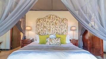 A bedroom with a canopy bed, two bedside tables with lamps, and a floral-patterned headboard.