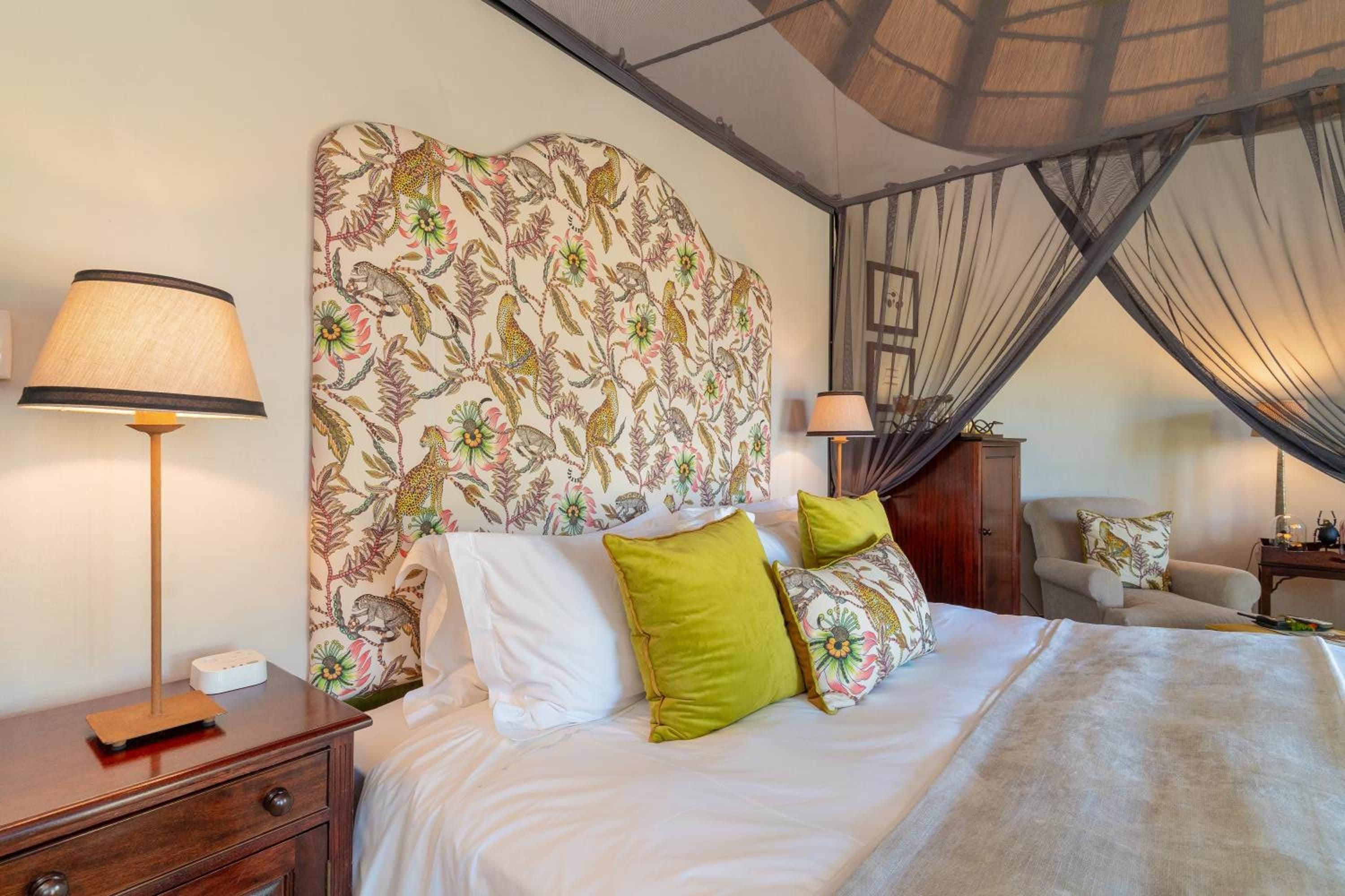 Une chambre à coucher avec un lit à baldaquin, une table de chevet, une lampe et une chaise.