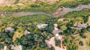 Oversigtsbillede af et boligområde med flere huse, en swimmingpool og en flod.