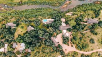 Luchtbeeld van een woongebied met meerdere huizen, een zwembad en een rivier.
