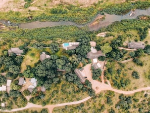 Luchtbeeld van een woongebied met meerdere huizen, een zwembad en een rivier.
