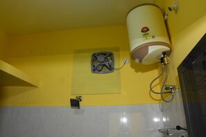 Ein Badezimmer mit gelber Wand, weißen Fliesen, einer Dusche und einem WC.