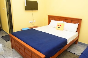 Ein Einzelbett mit Holz Kopfteil, einer blauen Bettdecke und einem Kopfkissen mit Herzmuster.