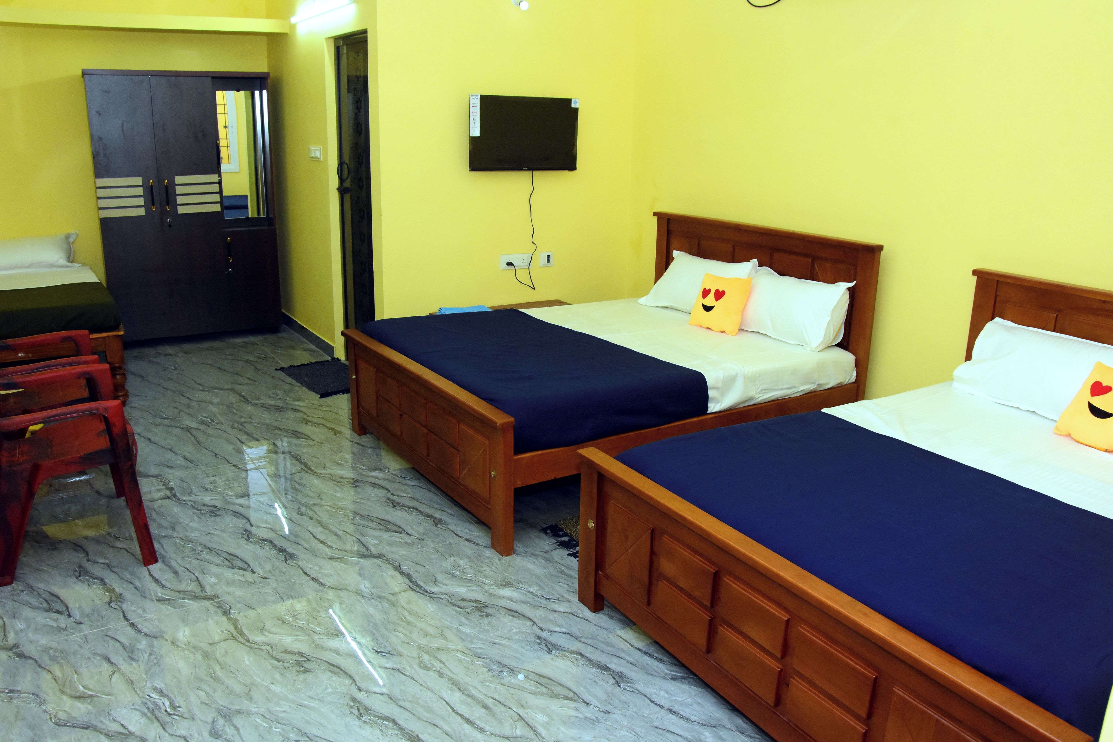 A hotel room with two beds, a desk, a chair, and a television on the wall.