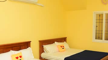 Una habitación con dos camas de madera, ventilador de techo, aire acondicionado y una ventana con rejas.