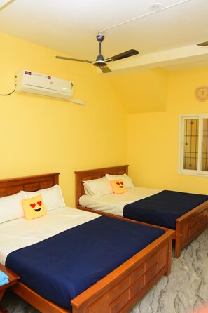 Ein Zimmer mit zwei Holzbetten, einem Deckenventilator, einer Klimaanlage und einem Fenster mit Gitterstäben.