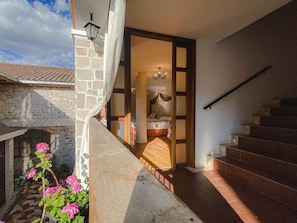 Una casa de piedra con una escalera que lleva a un dormitorio con cama y candelabro.