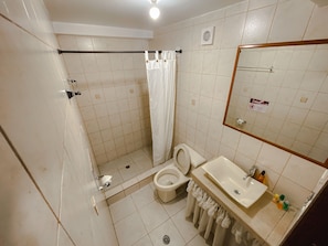 Un baño con ducha, inodoro, lavamanos y espejo.
