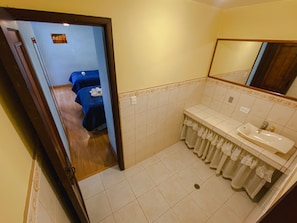 Casa de banho com lavatório, espelho e zona de duche.