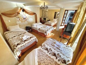 A hotel room with two beds, a chandelier, a desk, and a television. - Villa de Tacvnga Hotel (Latacunga)
