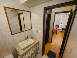 A bathroom with a white sink, a mirror, and a wooden door leading to another room. - Villa de Tacvnga Hotel (Latacunga)