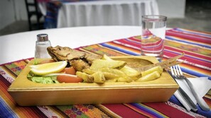 A meal with a plate of food, including a piece of meat, fries, and vegetables, on a colorful tablecloth. - Villa de Tacvnga Hotel (Latacunga)