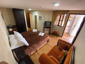 Habitación de hotel con cama, televisión, escritorio, silla y vista al exterior.