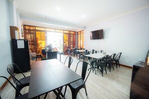 Un salón de conferencias con una gran mesa y sillas, un refrigerador y un televisor en la pared.