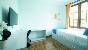 A room with a bed, a desk, a chair, a television, and a window with curtains. - Rehat at Zeva Guest House (Bandung)
