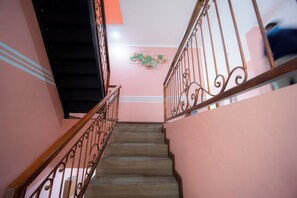 A staircase with wooden steps and metal railings, leading to a landing with a decorative wall. - Rehat at Zeva Guest House (Bandung)