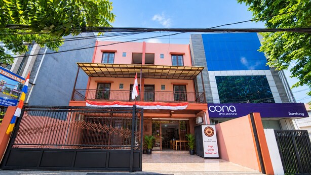 A two-story building with a covered entrance and a sign for 'Kopi Cerita Setiap Hari'. - Rehat at Zeva Guest House (Bandung)
