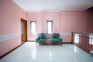 A room with pink walls, a wooden bench with green cushions, a wooden door, and a window. - Rehat at Zeva Guest House (Bandung)