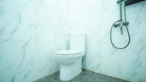 A bathroom with a toilet, a shower, and a tiled floor. - Rehat at Zeva Guest House (Bandung)