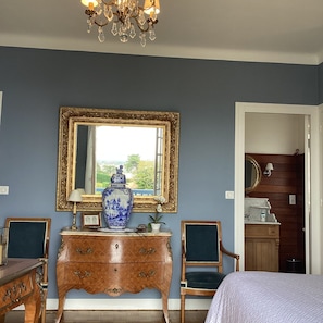 A bedroom with a large bed, a dresser, a mirror, and a chandelier. - L'Annexe – Bed and Breakfast with a View of the Bay of Saint-Jean-de-Luz (Ciboure, Sud Ouest de France, France)