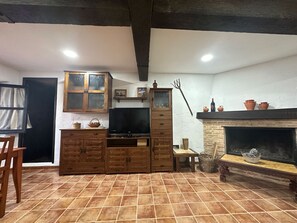 A rustic room with a fireplace, wooden cabinets, and a television. - Holiday Home 'Alojamiento Rural La Tinaja' with Mountain View, Private Pool and Wi-Fi (Moriscote)
