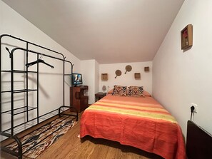A bedroom with a bed, a metal wardrobe, a television, and a patterned rug. - Holiday Home 'Alojamiento Rural La Tinaja' with Mountain View, Private Pool and Wi-Fi (Moriscote)
