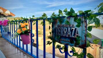 A blue metal railing with potted plants and a sign with text.